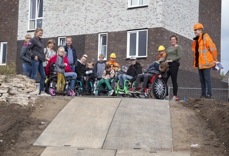 Ontwerpers, bouwers en kinderen in rolstoelen staan klaar om de helling uit te proberen