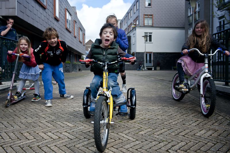 Jongetje met een beperking fietst op zijn driewieler met zijn fietsende vriendjes